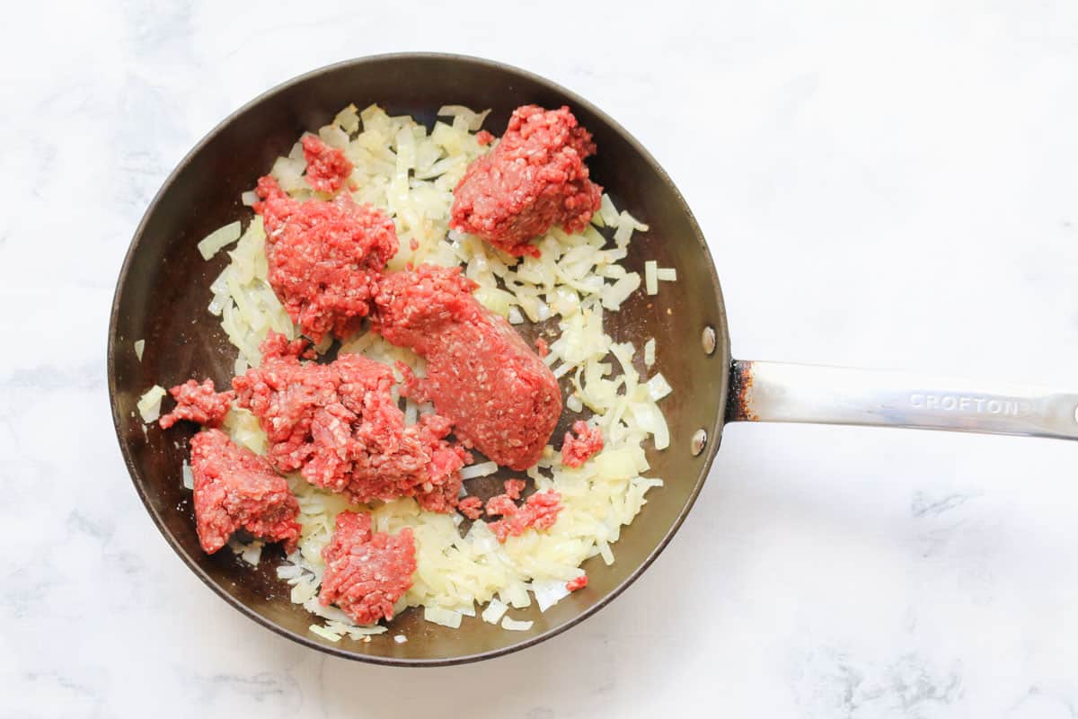 raw mince added to a frying pan with softened onion