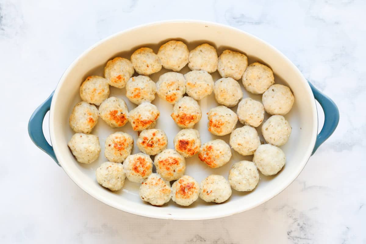 Baked chicken meatballs in a baking dish.