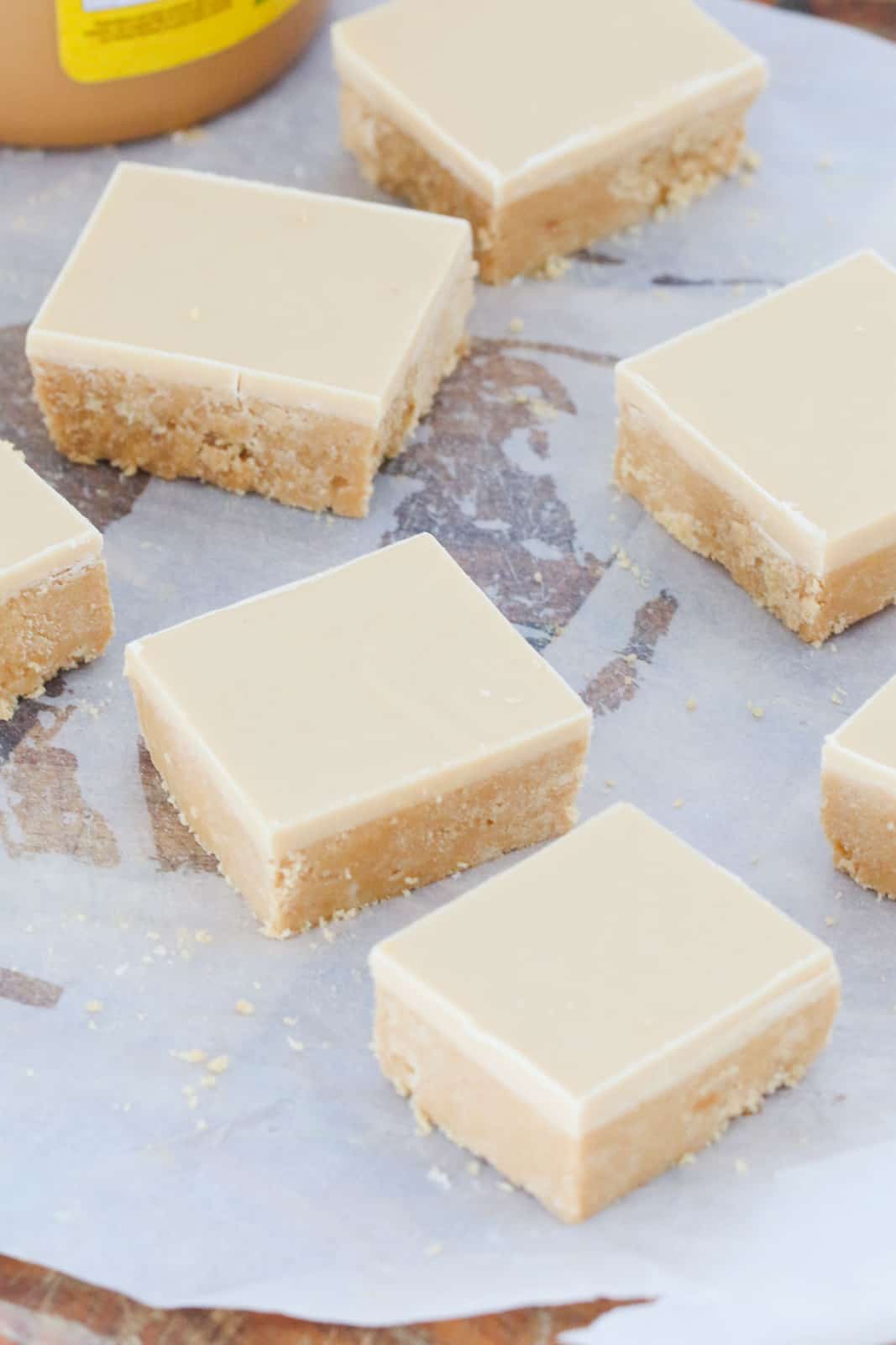 A white chocolate and peanut slice cut into squares on a chopping board.