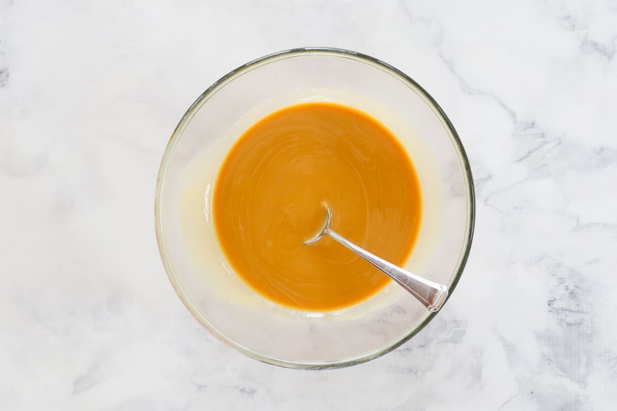 Melted butter and peanut butter in a bowl with a spoon.