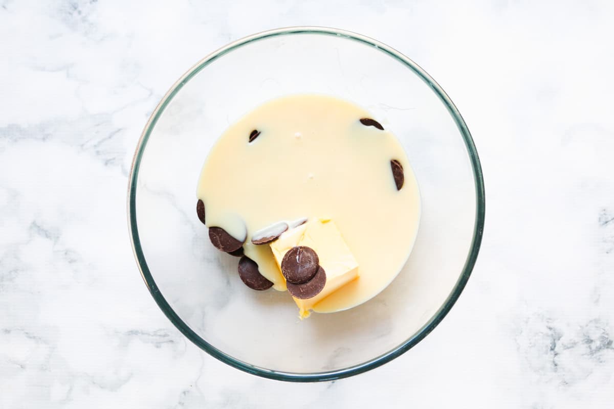 Condensed milk, butter and chocolate in a glass bowl.