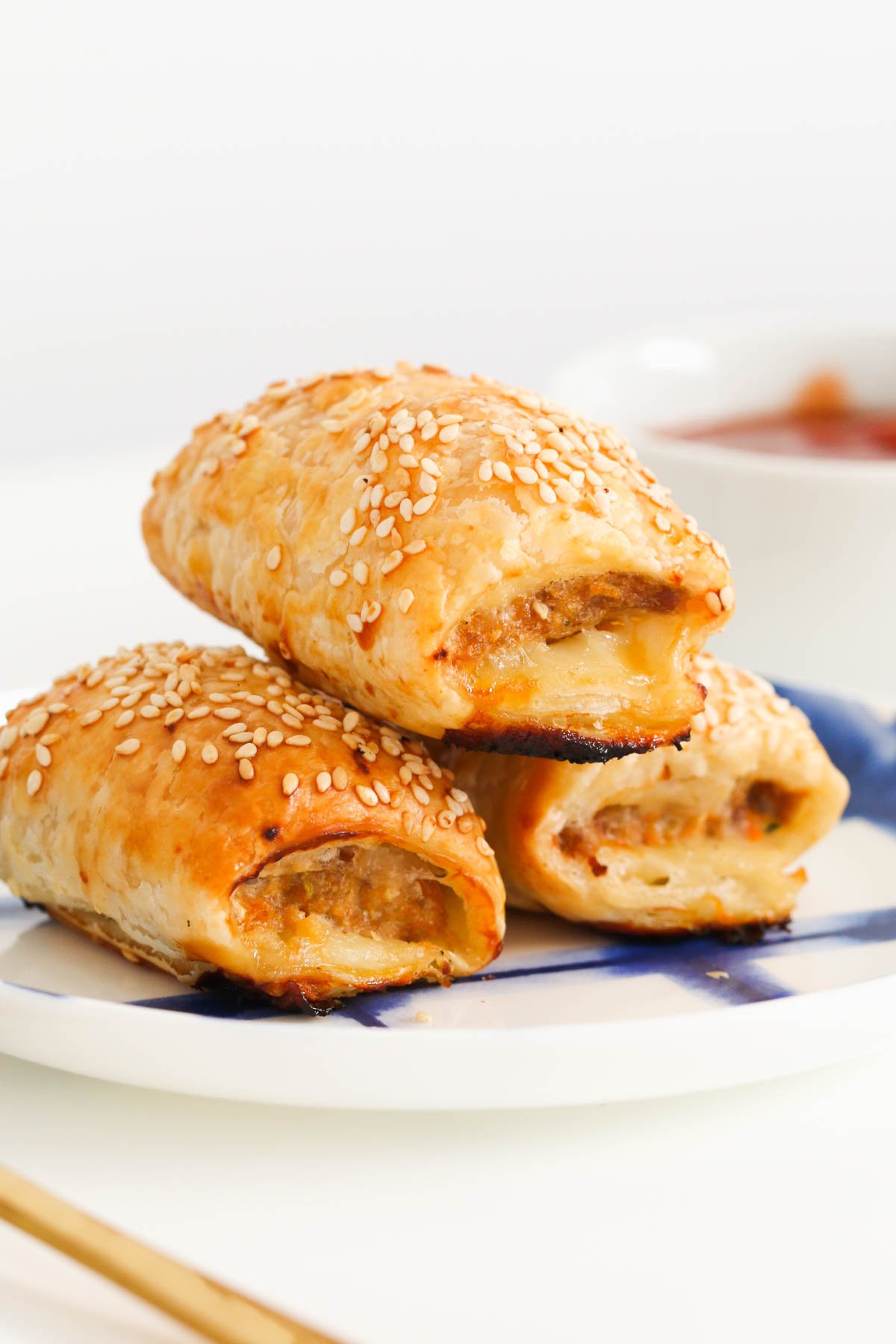 Three savoury, sesame seed crusted pastries on a blue and white plate