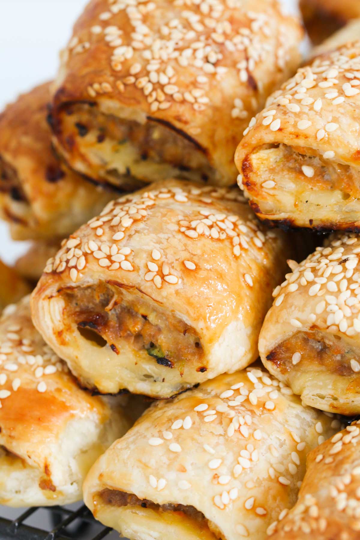 A zoomed in image of golden chicken sausage rolls stacked on top of each other