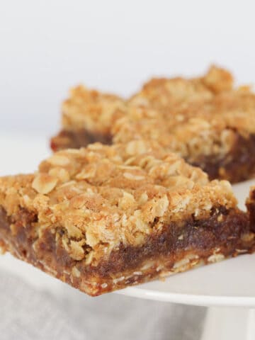 A piece of crumble slice with a date filling.
