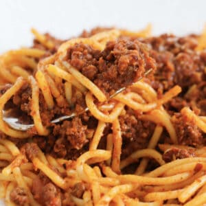 A bowl of pasta coated in a meat and tomato sauce.