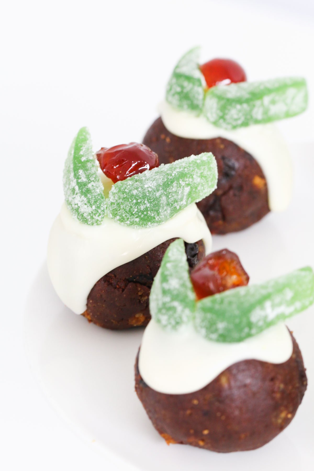 Christmas pudding balls decorated with whte chocolate, spearmint leaves and a glace cherry.
