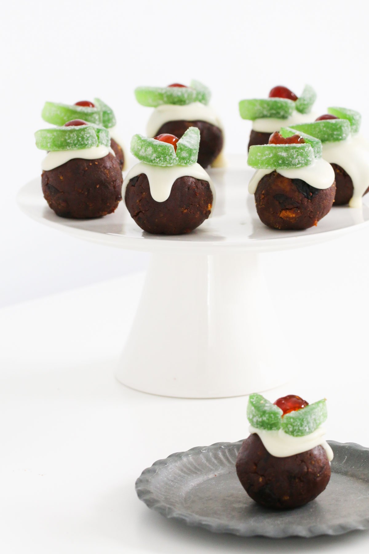 A cake stand of Christmas puddings with another on a plate in front.