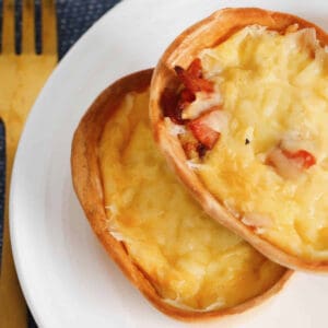 An overhead picture of two cheesy egg and bacon tortilla shell quiches