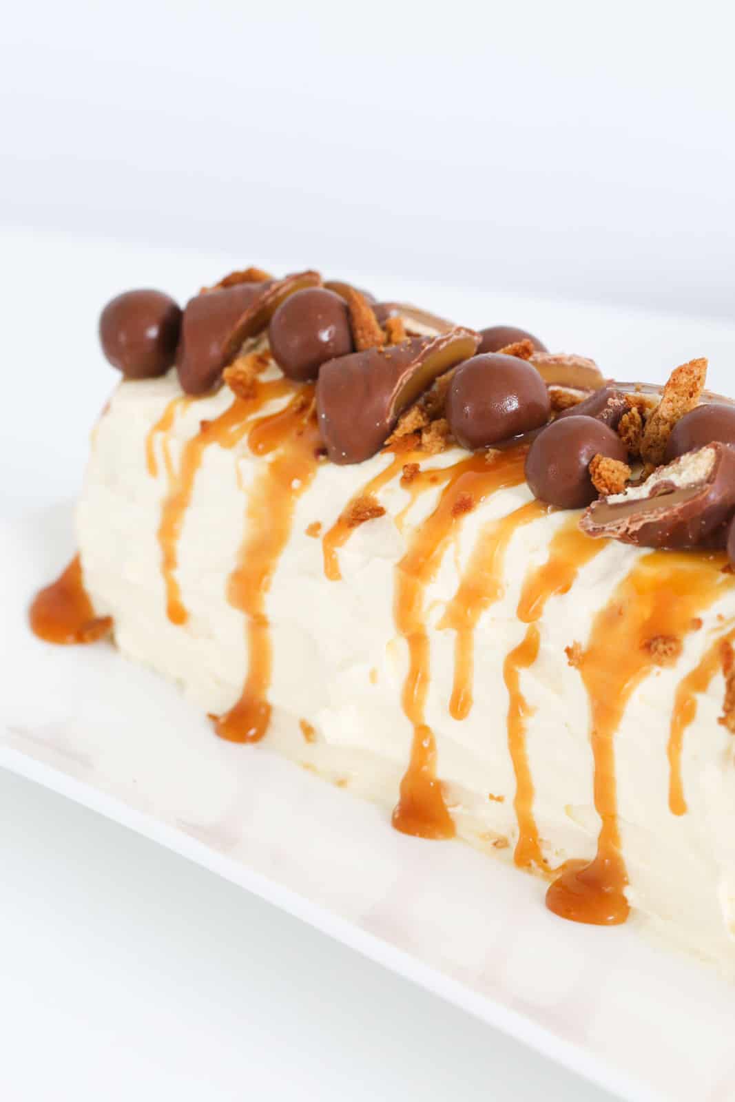 Chocolates and caramel sauce on top of a whipped cream chilled dessert.