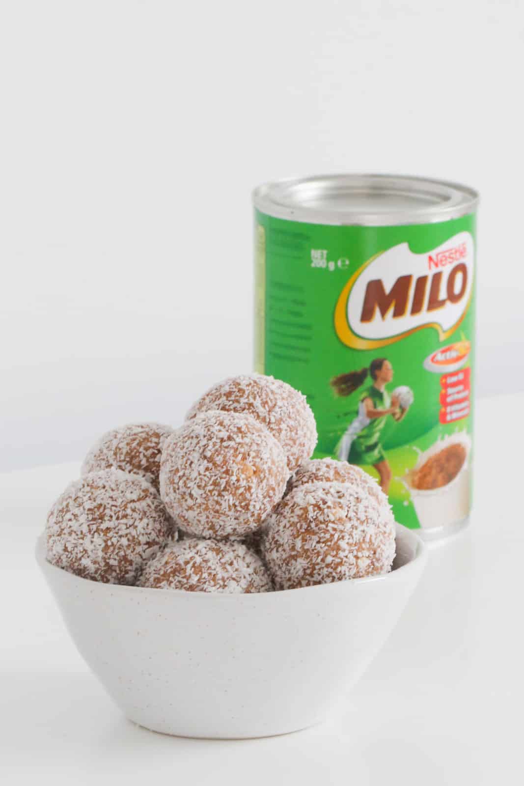 A tin of Milo behind a bowl of malted milk, coconut and biscuit balls.