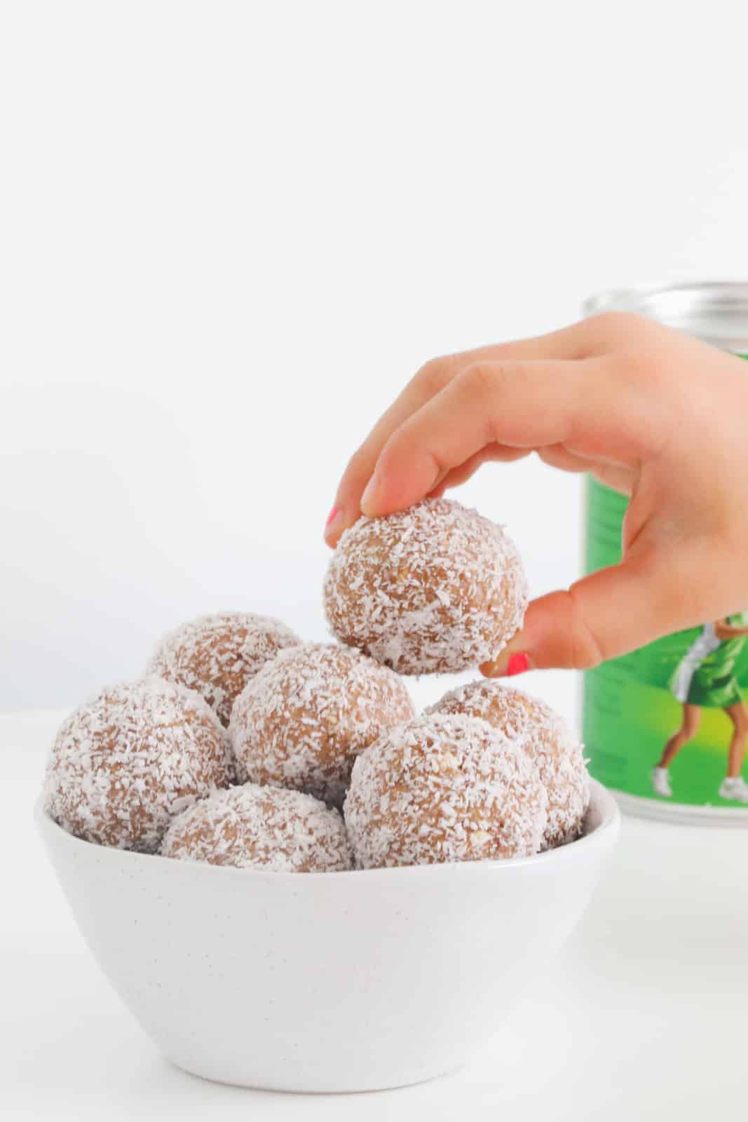 A hand reaching for a chocolate ball coated in coconut.