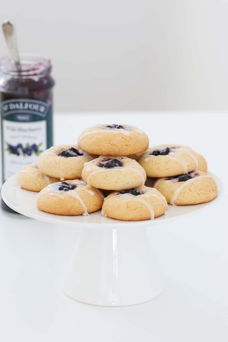 A batch of blueberry and lemon cookies on a white cake stand.