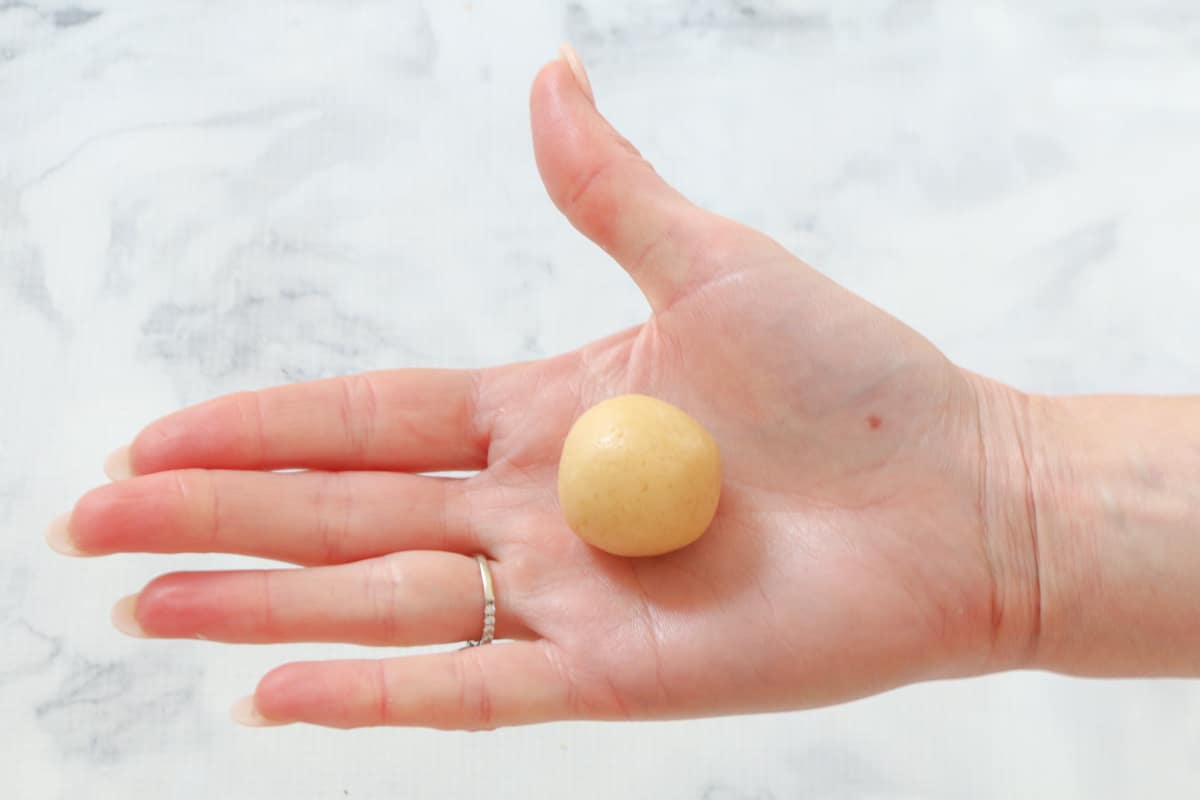 A ball of cookie dough in the palm of a a hand.
