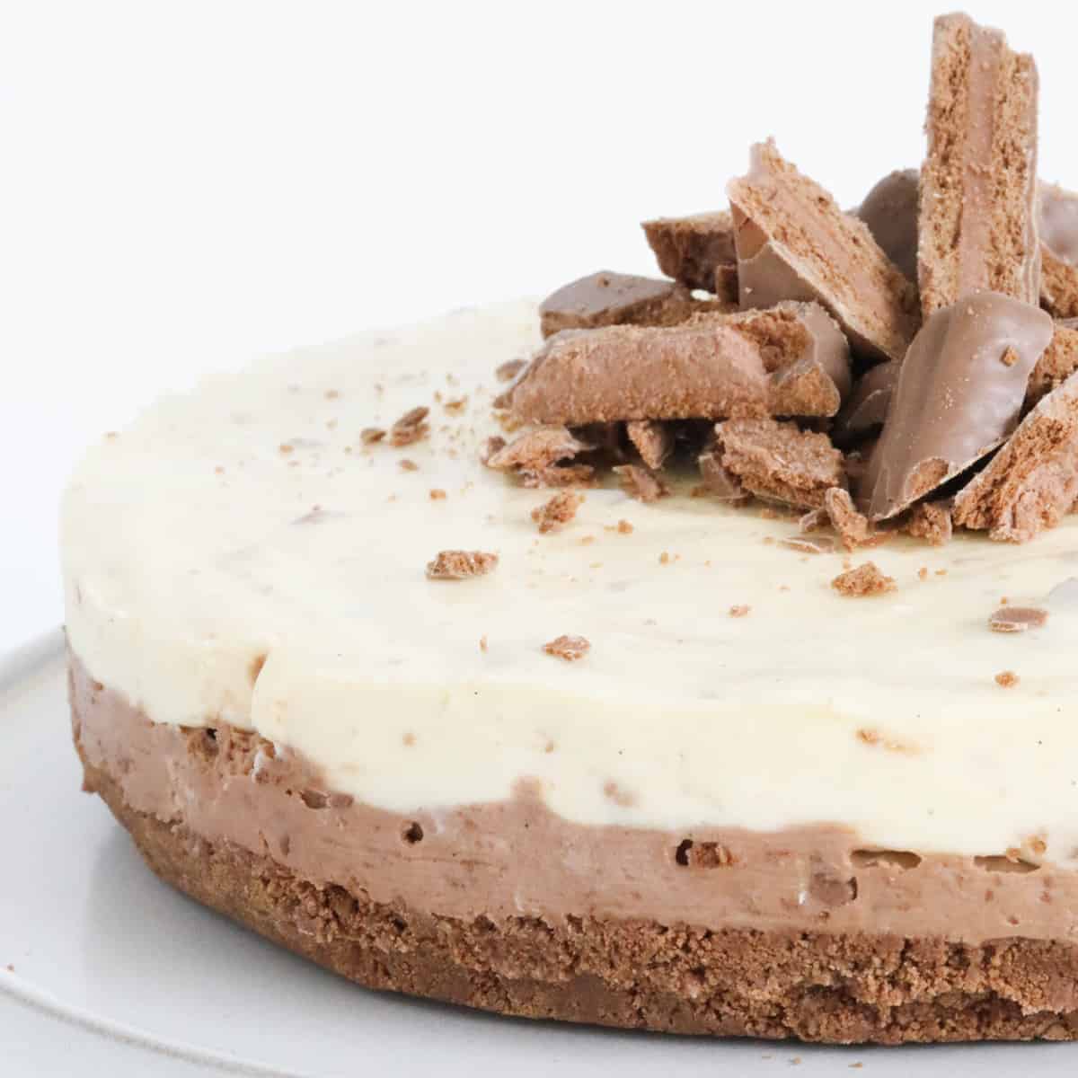 A close up view of a double layered cheesecake with chocolate biscuits on top.