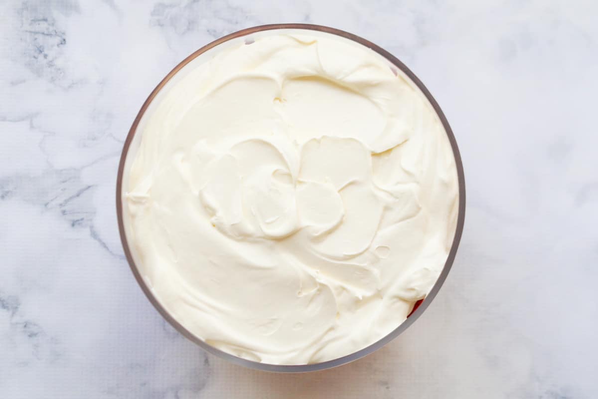 A layer of whipped cream on top of trifle base.