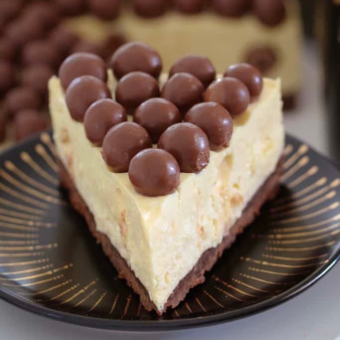 A slice of Baileys Malteser Cheesecake with Maltesers on top.