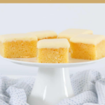 Squares of baked lemon slice with lemon frosting, served on a white cake stand