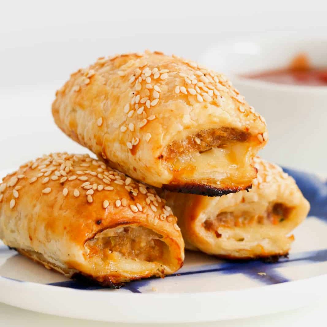 zoomed in image of three chicken sausage rolls on a blue and white plate
