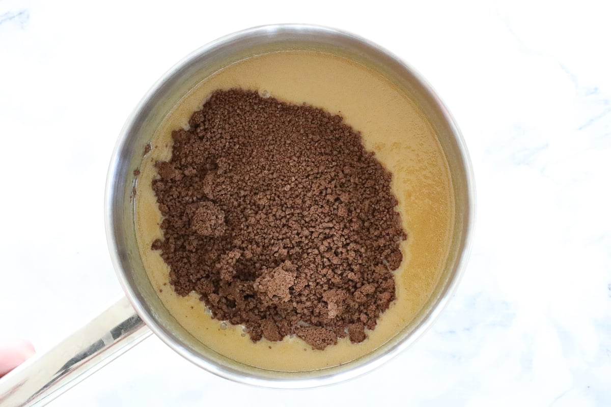 Grated chocolate sprinkled over caramel in a saucepan.