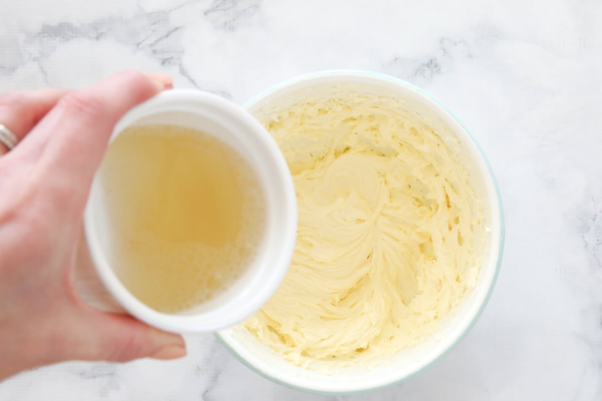 Gelatine dissolved in water in a ramekin being added to a cream cheese and sugar mixture