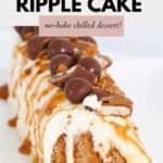 A cream covered dessert log, decorated with chocolates and drizzled with caramel sauce.