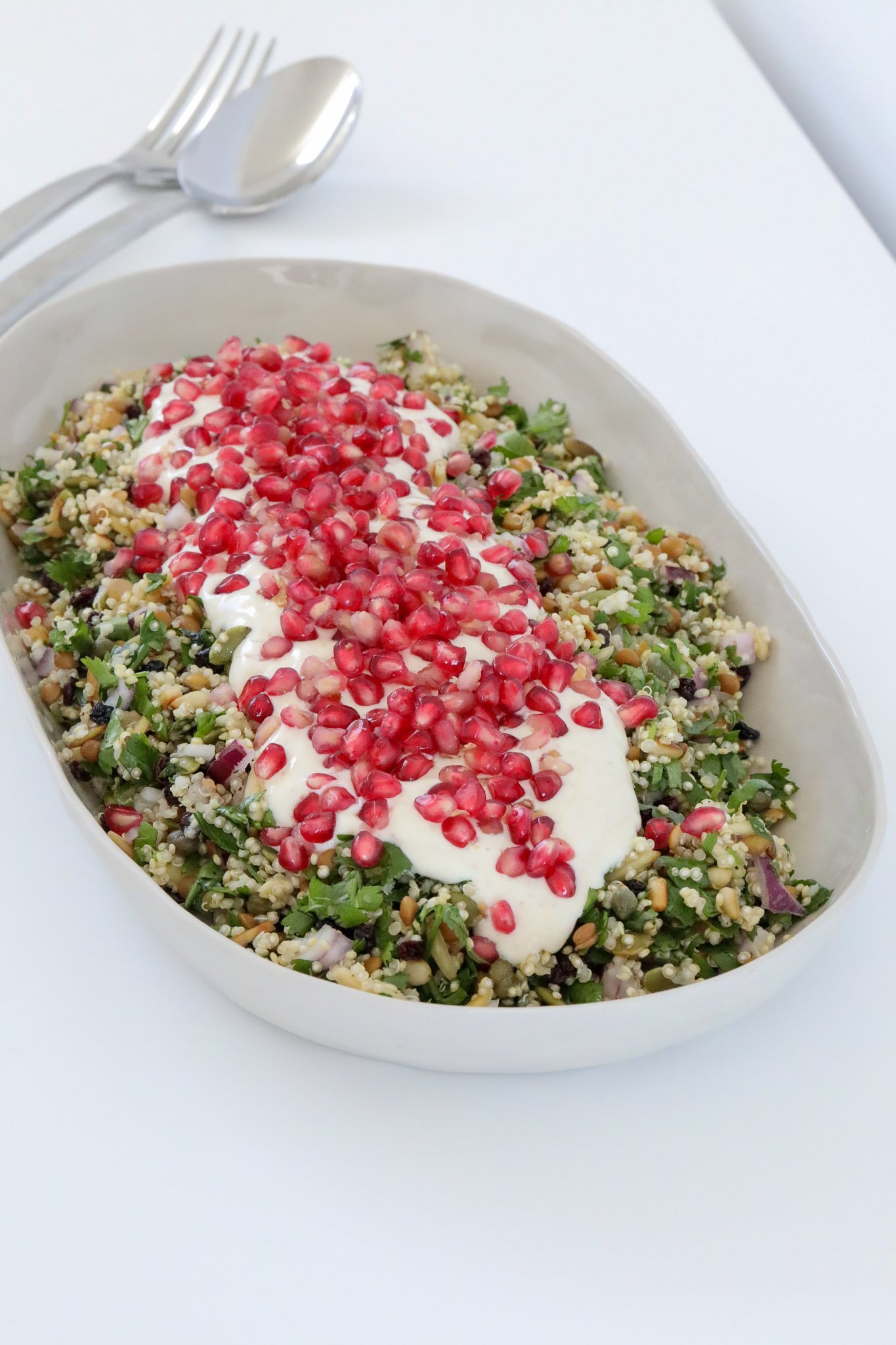 A grain and herbs salad topped with pomegranates and greek yoghurt.