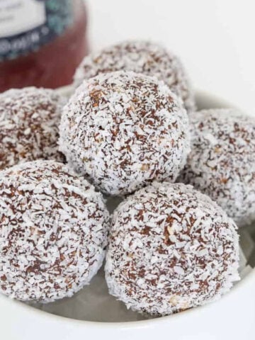 A bowl of chocolate balls coated in coconut.