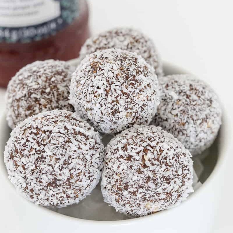 A bowl of chocolate balls coated in coconut.