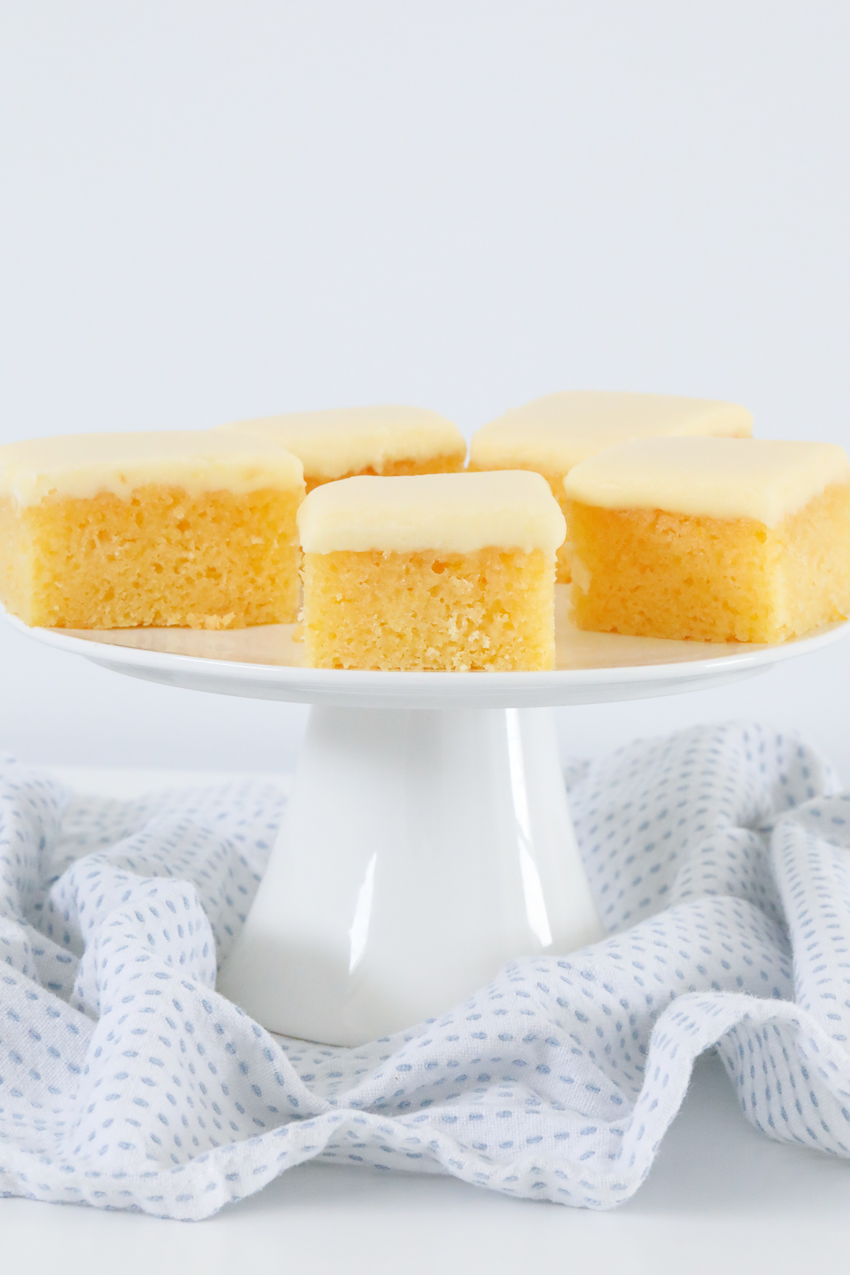 Lemon frosting on pieces of a golden slice, served on a cake stand