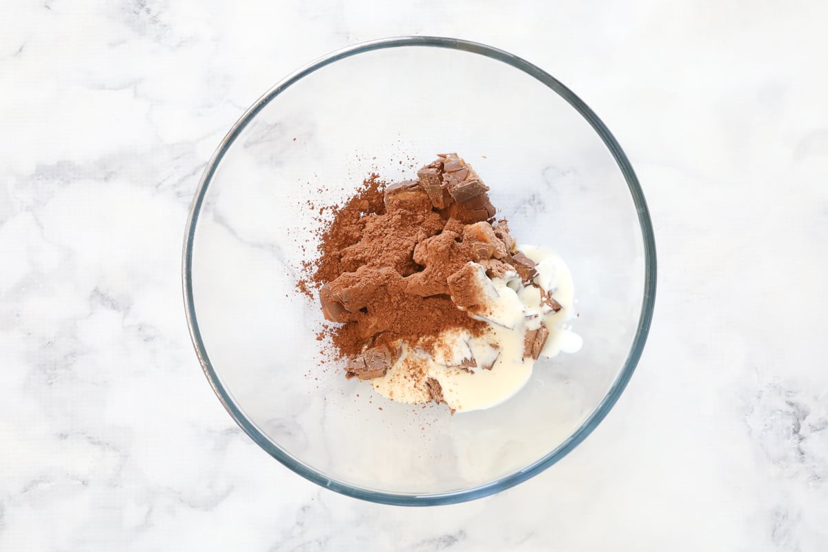 Cream, cocoa powder and chopped Mars Bars in a bowl.