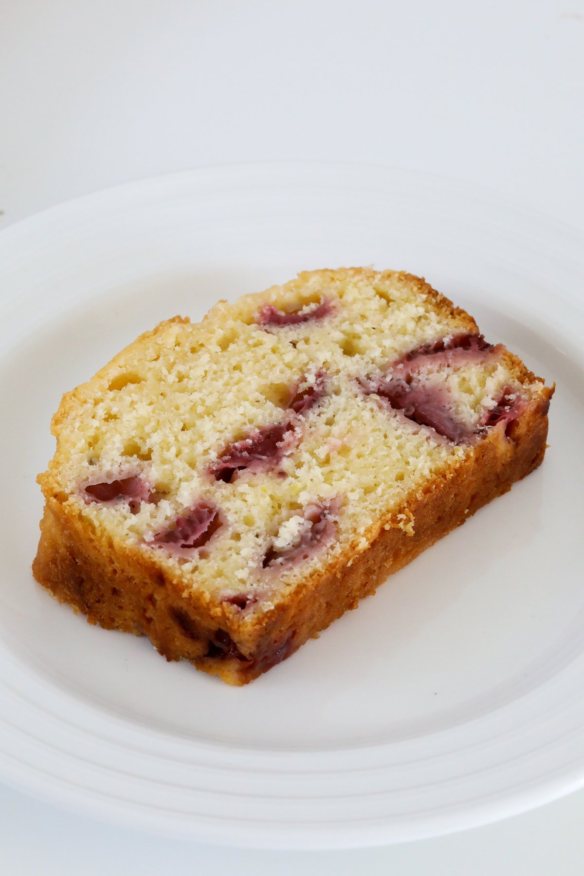 A slice of strawberry loaf on a white plate.