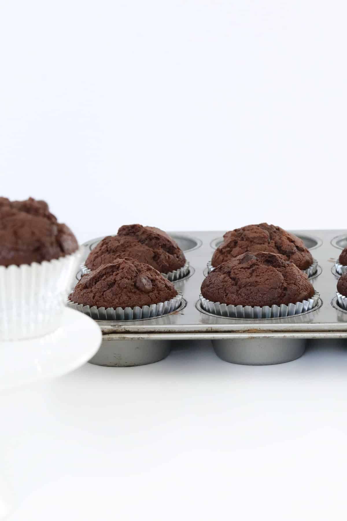 Chocolate chip muffins in silver muffin cases in a baking tray