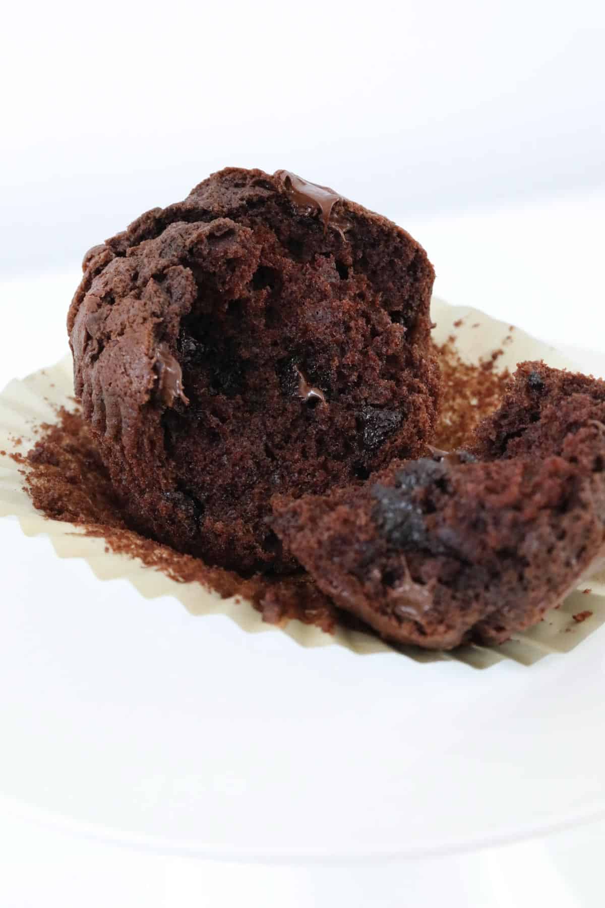 A chocolate muffin broken in half in a muffin paper case