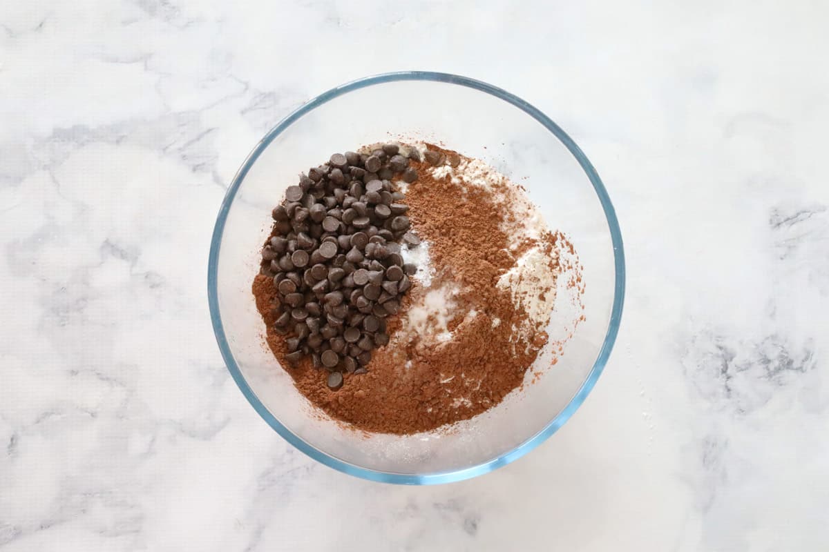 Cocoa, chocolate chips and dry ingredients in a glass bowl