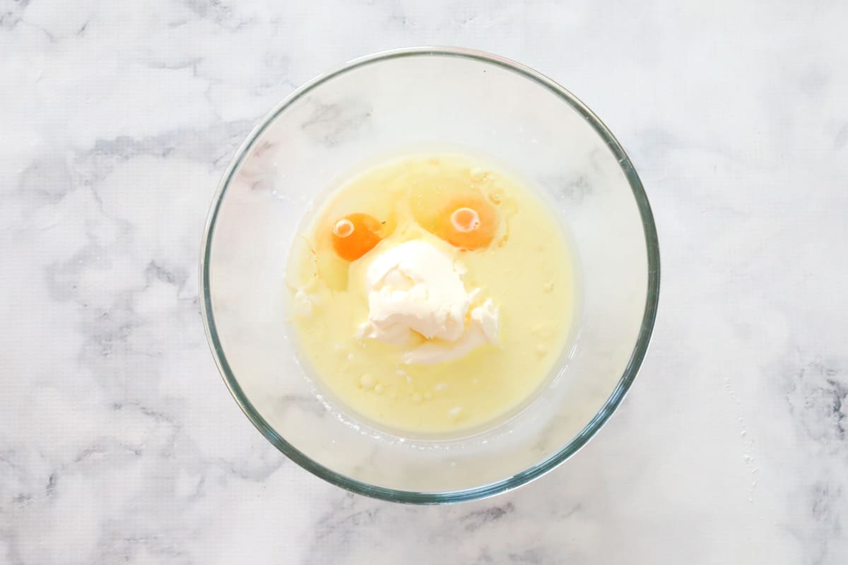 Eggs, sour cream, oil and milk in a glass bowl