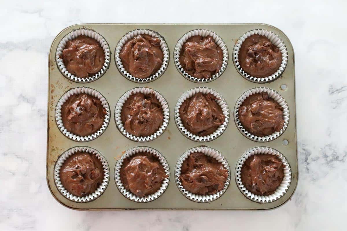 Top view of a muffin tray with individual cases filled with batter