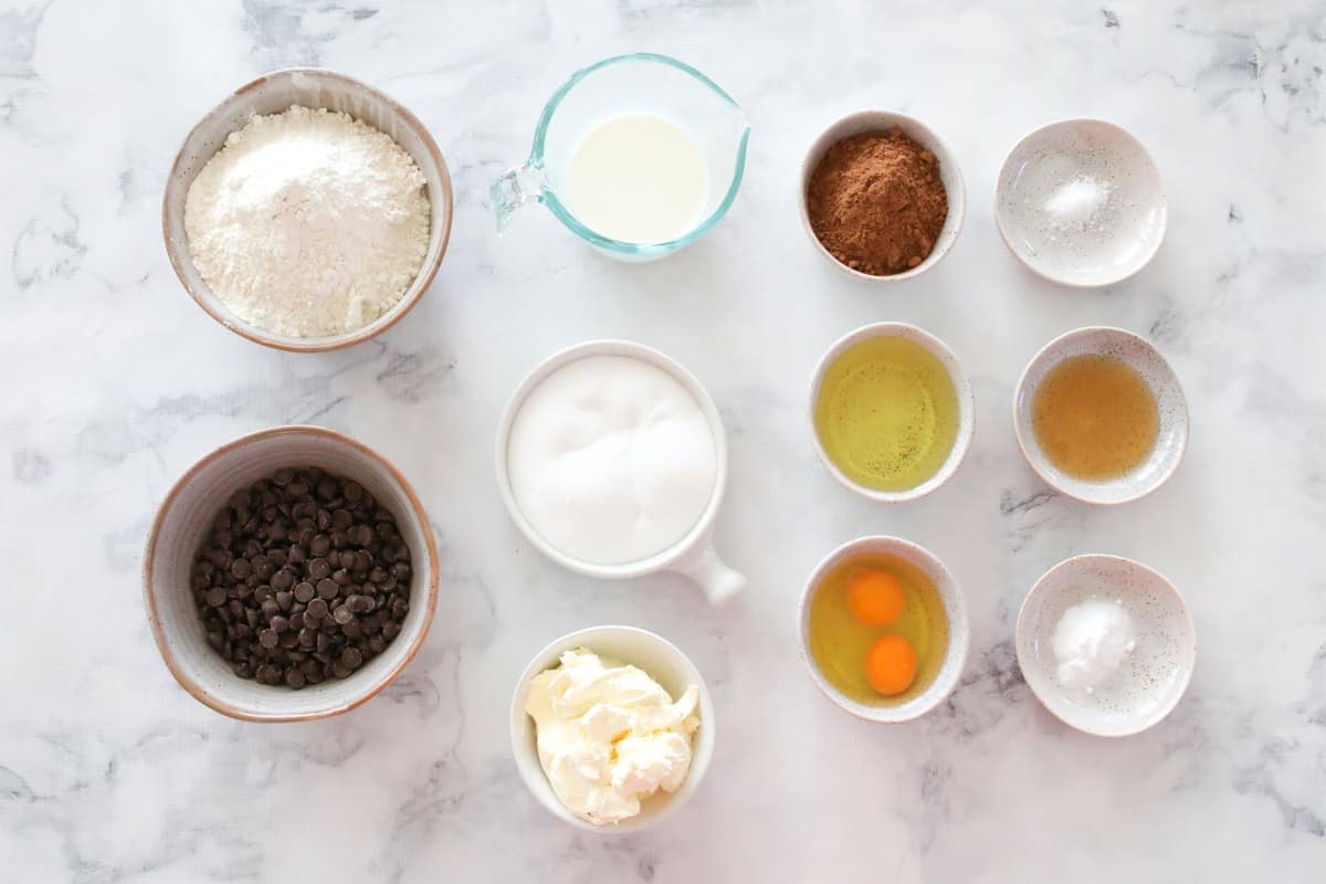 All ingredients for double chocolate chip muffins laid out on a table in individual bowls