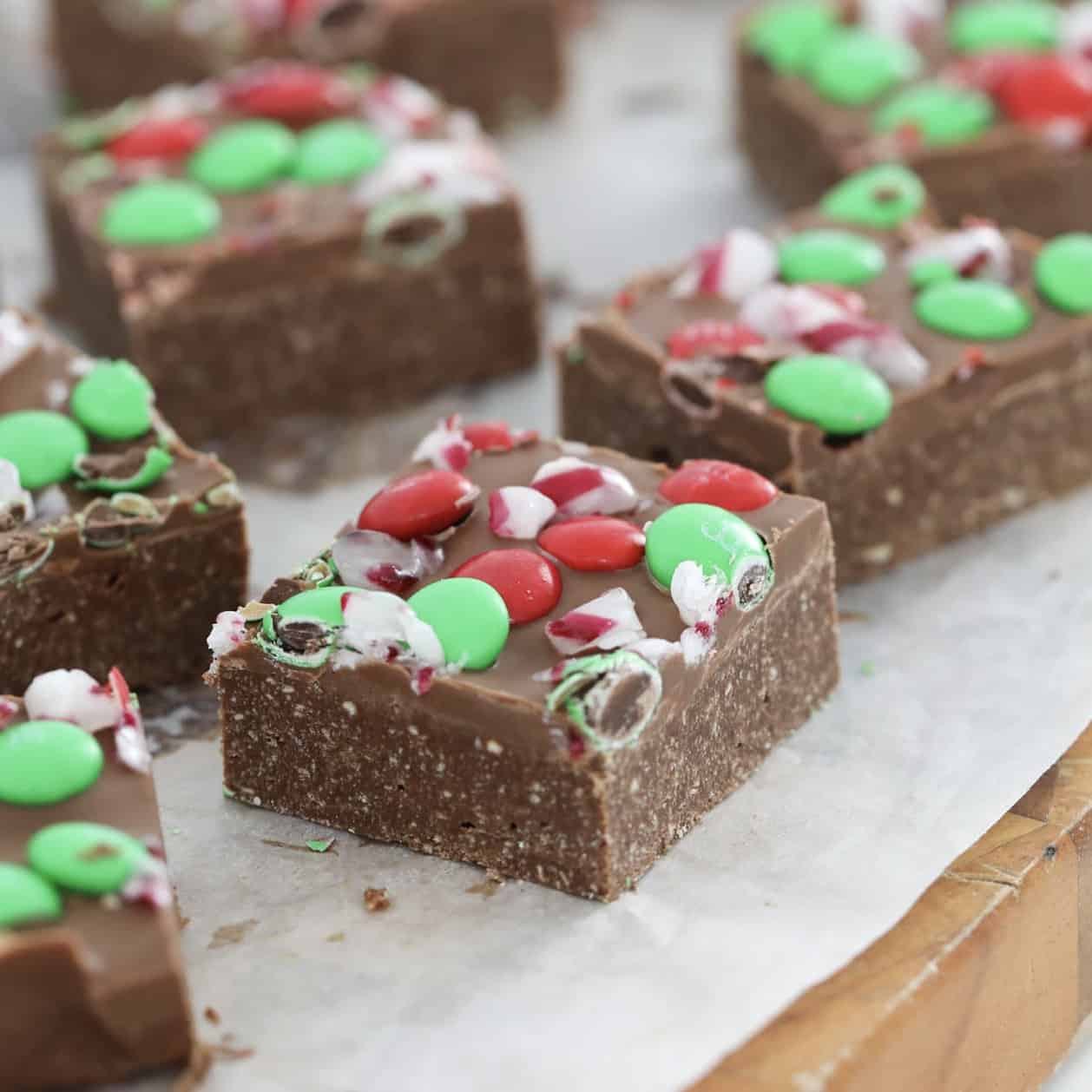 pieces of Christmas slice on a wooden board topped with red and green chocolate