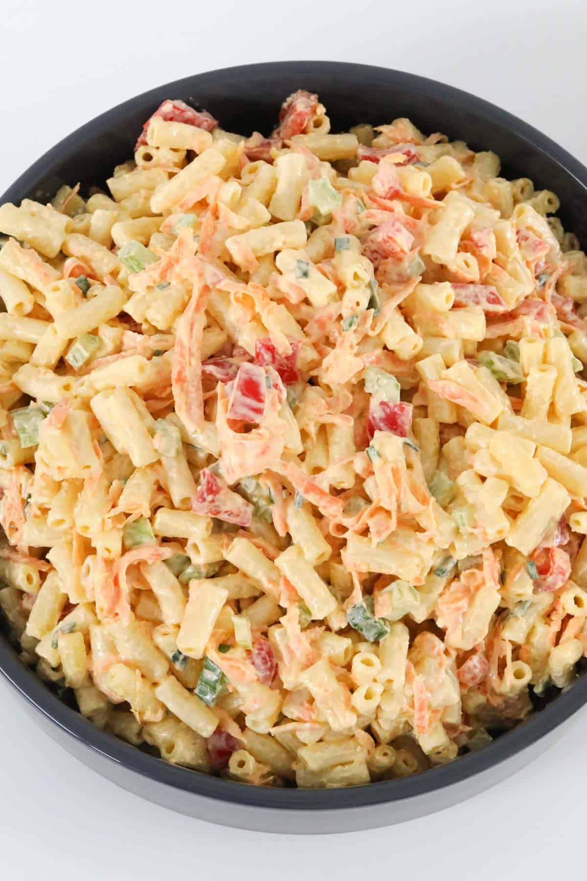 Overhead view of creamy pasta salad in a black bowl