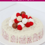 A festive ice-cream cake with white chocolate drizzled over and decorated with mini meringues, Lindt Balls and fresh raspberries