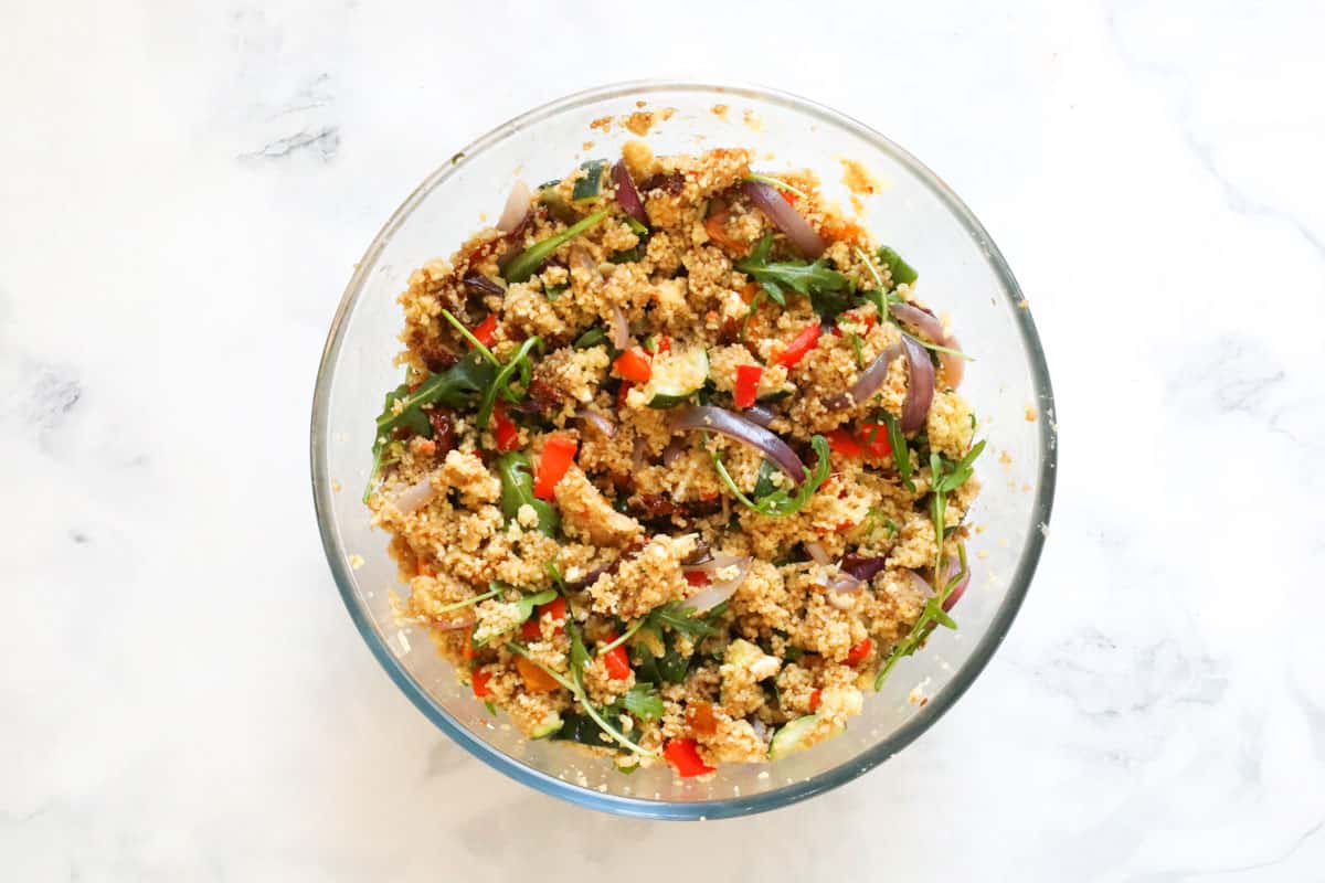 Roasted vegetables, rocket and couscous combined in a glass bowl