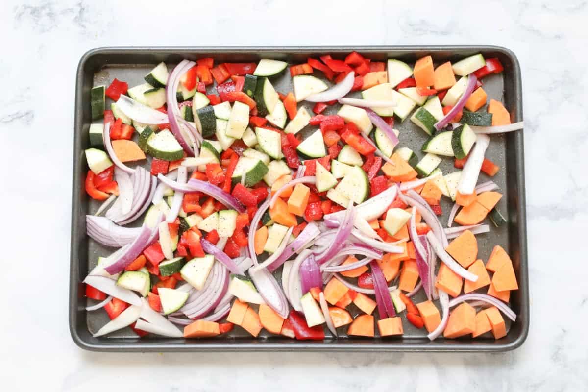 A baking tray with chopped vegetables scattered all over it