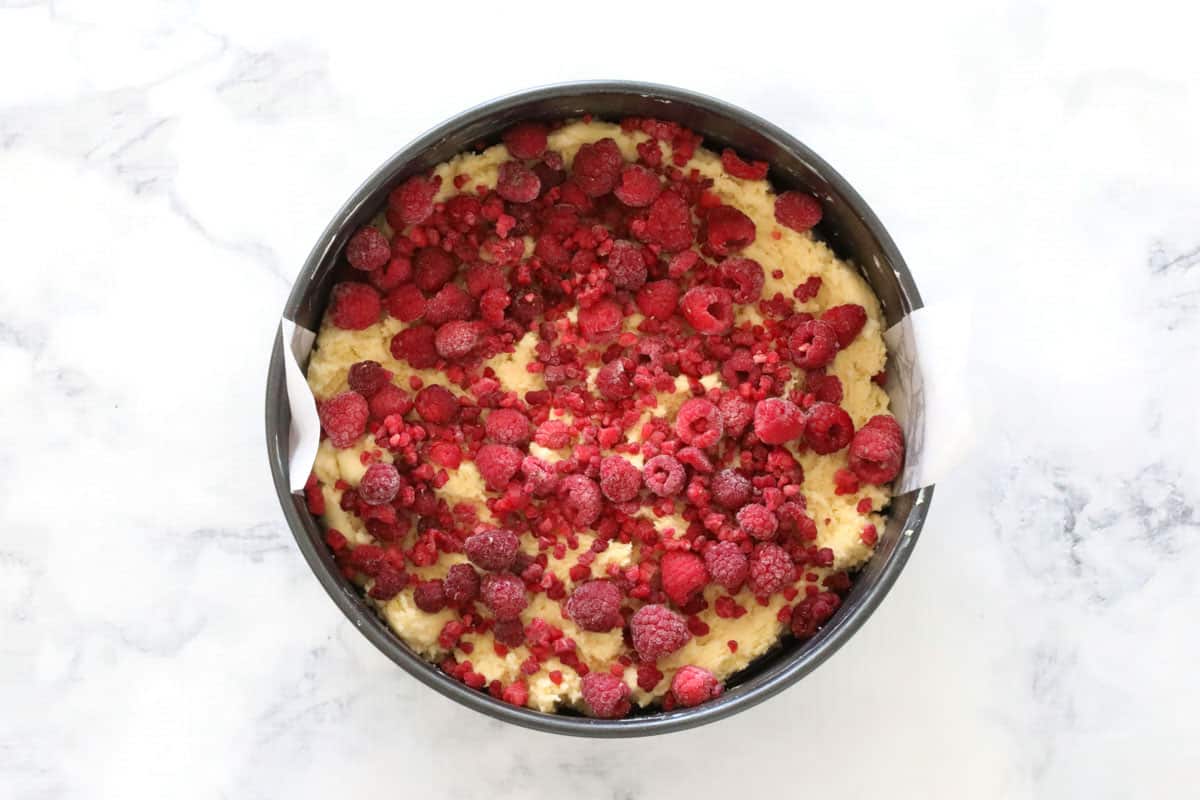 Frozen raspberries layered over cake batter in tin