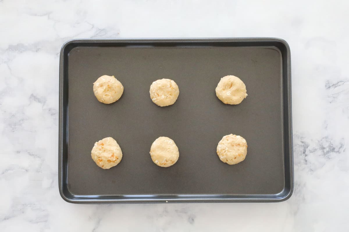 Six unbaked balls of cookie dough on a baking tray.