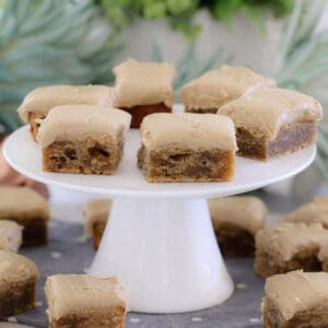 A white cake stand topped with pieces of banana slice with caramel frosting.