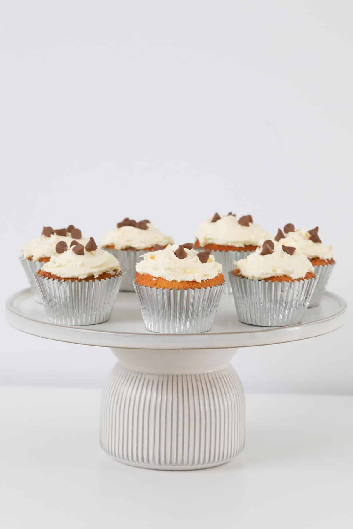 Cupcakes topped with chocolate chips on a white cake stand