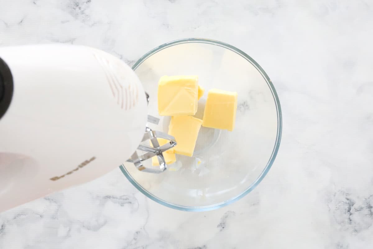 Electric mixers beating butter in a glass bowl