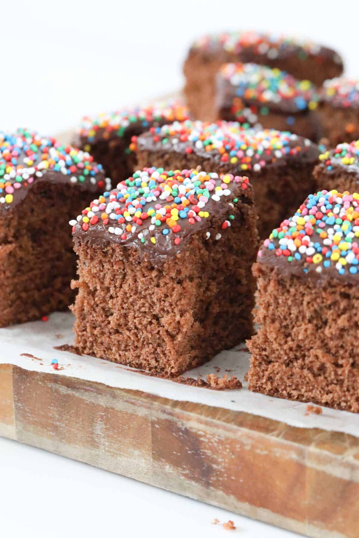 Slices of fluffy chocolate cake topped with icing and sprinkles