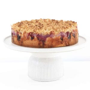A raspberry crumble cake with apple on a cake plate.