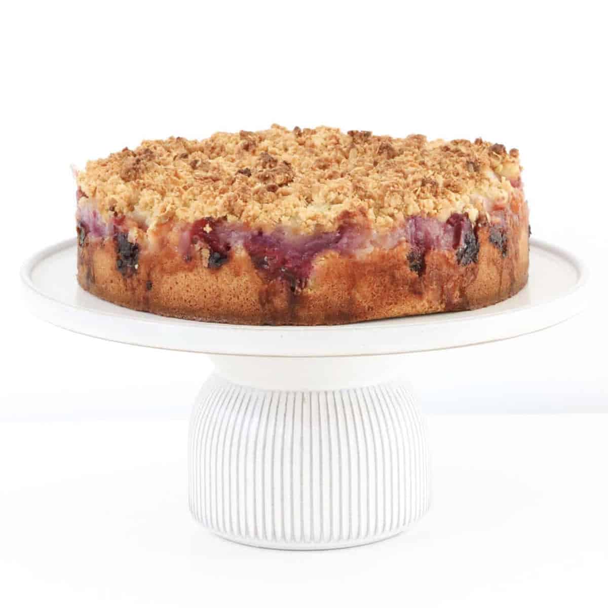 A raspberry crumble cake with apple on a cake plate.